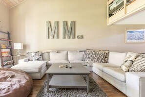 Uma sala de estar com sofá seccional, mesa de centro e uma grande decoração de parede.