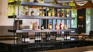 Un espace bar avec des étagères remplies de bouteilles d’alcool et des plantes suspendues.