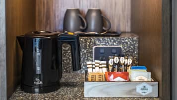 Une machine à café, deux tasses et une boîte de capsules de café sont posés sur un plan de travail.