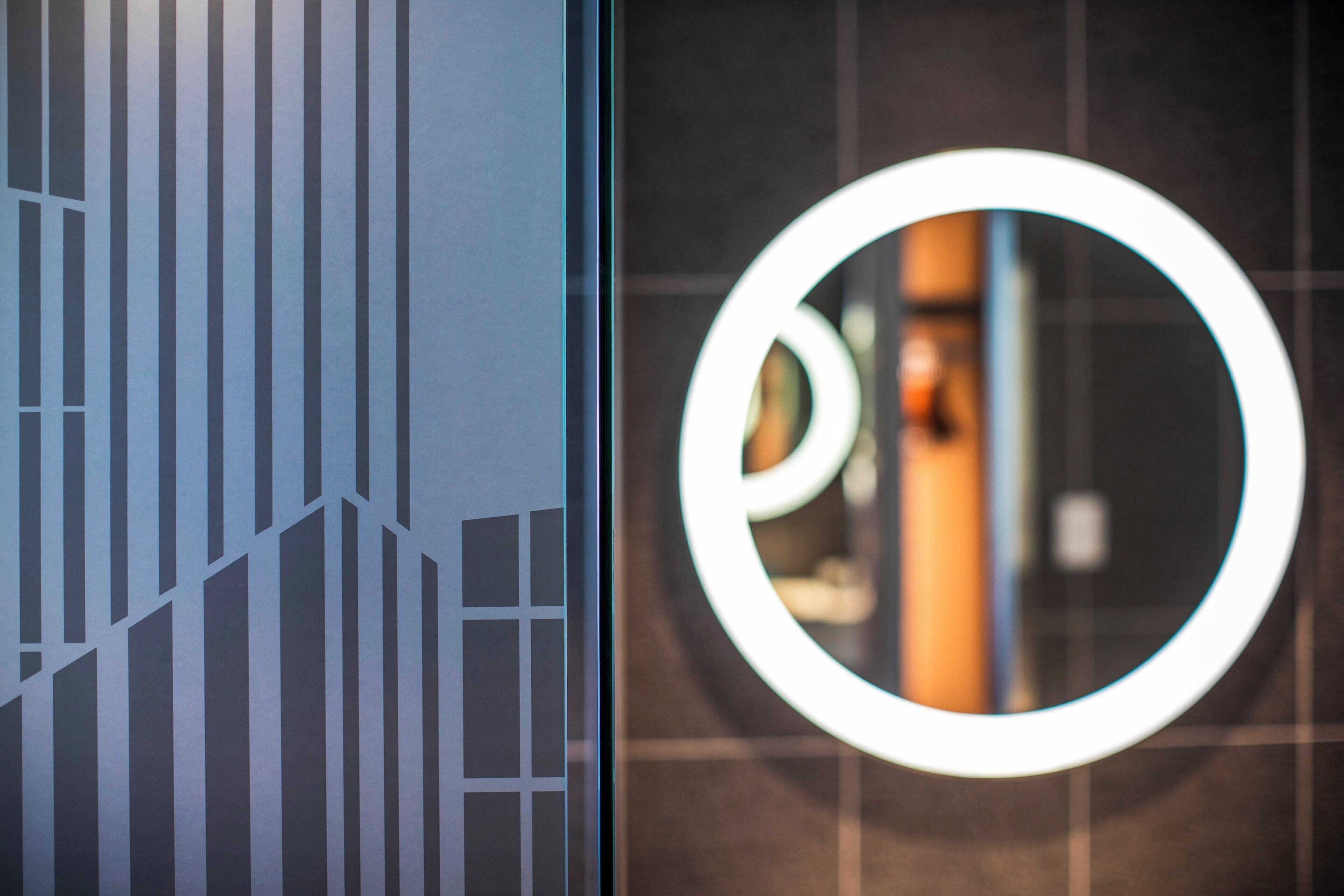 A modern building facade with a geometric pattern and a circular logo.