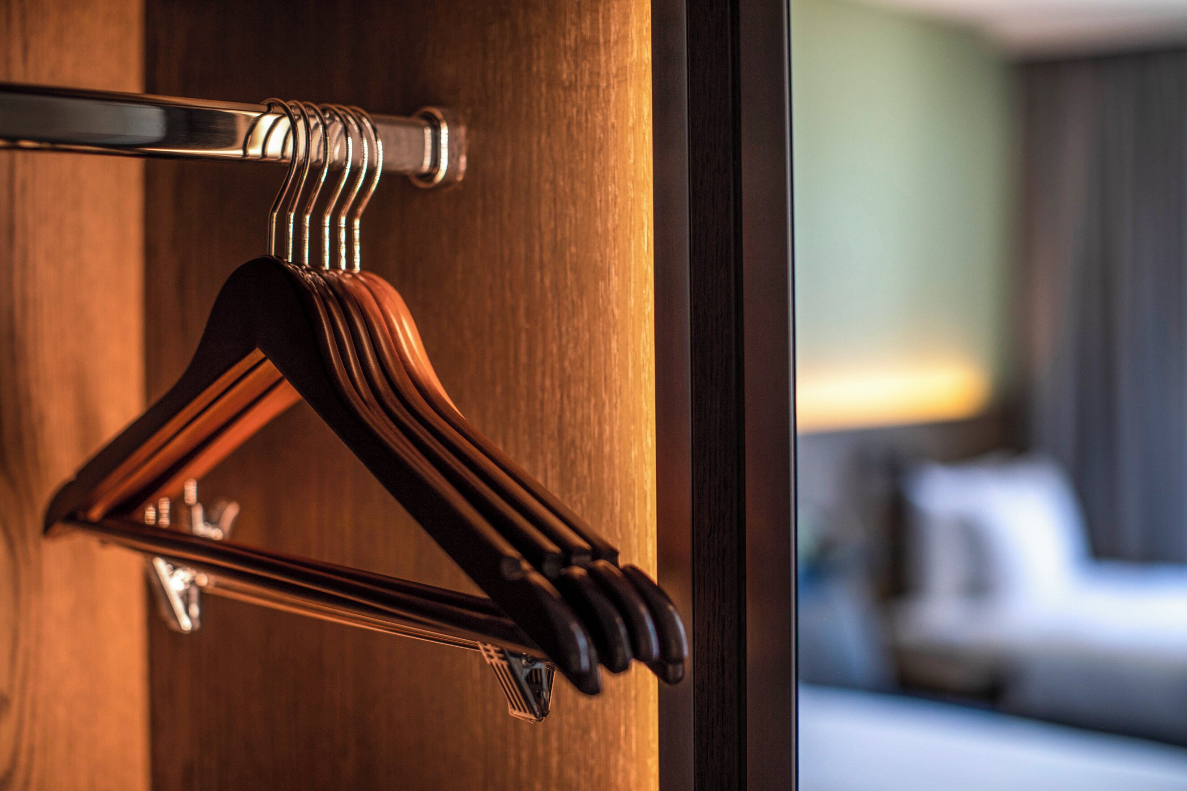 A wooden door with a metal hanger holding three brown hangers.