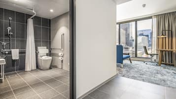 A modern bathroom with a shower, toilet, and handrails.