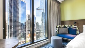 A hotel room with a large window, a sofa, a round table, and a bed. - Holiday Inn Express Melbourne Little Collins by IHG (Melbourne)