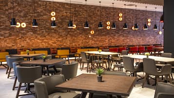 A modern restaurant with brick walls, wooden tables, and black pendant lighting.
