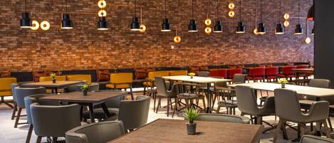 Um restaurante moderno com paredes de tijolo, mesas de madeira e luminárias pendentes pretas.