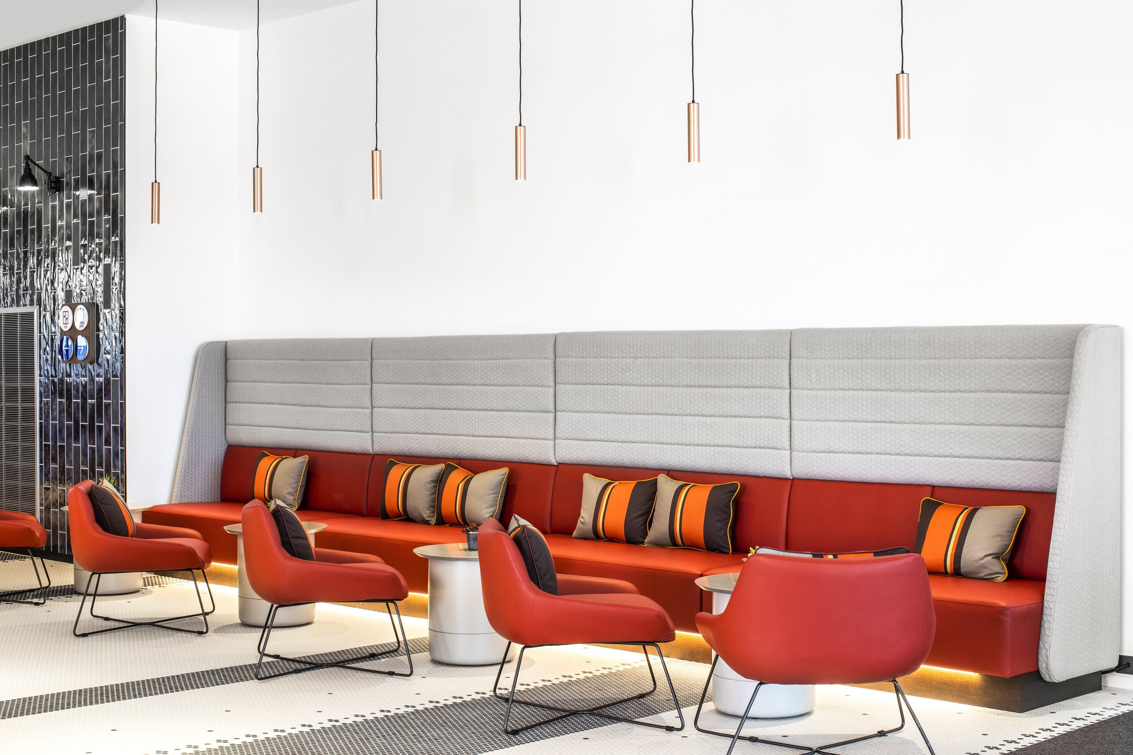 Un área de estar moderna con un sofá rojo, sillas rojas y un suelo estampado.