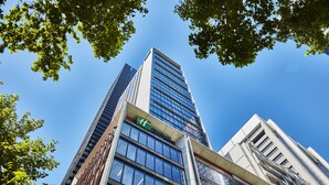 A high-rise hotel with a prominent 'H' logo, large glass windows, and a modern architectural design. - Holiday Inn Express Melbourne Little Collins by IHG (Melbourne)