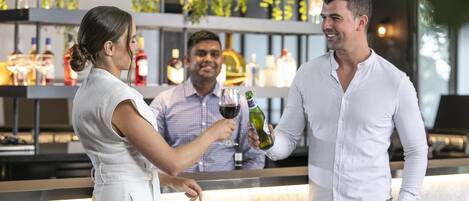 A bar area with a counter, shelves with bottles, and a person serving drinks.