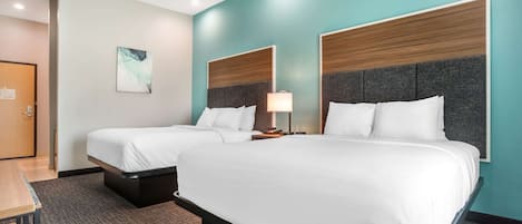 Habitación de hotel con dos camas, un escritorio y una puerta.