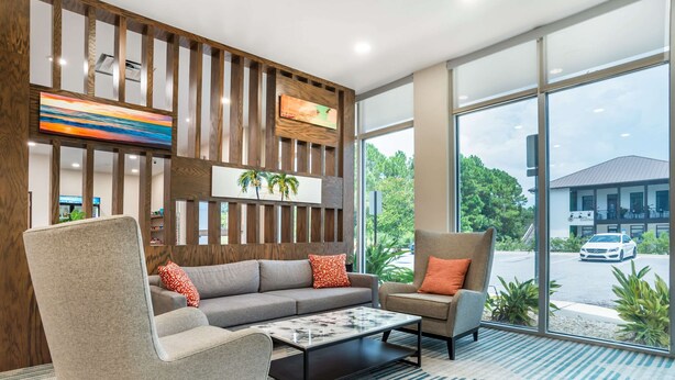 A modern lobby with a sofa, armchairs, a coffee table, and a large window with a view of the outside. - Comfort Inn Miramar Beach-Destin (Miramar Beach)