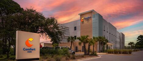 A Comfort Inn hotel with a modern design, featuring a large signboard and a parking area.