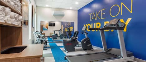 A gym with treadmills, stationary bikes, and a wall with motivational text.
