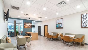 A modern indoor space with a reception desk, seating area, and a large window. - Comfort Inn Miramar Beach-Destin (Miramar Beach)