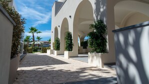 Un couloir extérieur abrité, doté d’arcades, d’un sol en pierre et de plantes en pot.