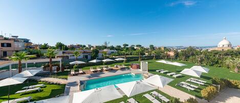 A resort with a swimming pool, sun loungers, umbrellas, and a dome-shaped building in the background.
