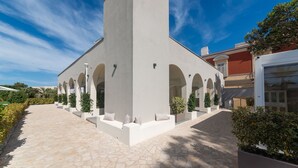 Un bâtiment moderne doté d’une tour centrale, de nombreuses arcades et d’une allée piétonne dallée.