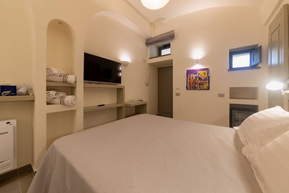 Habitación de hotel con cama, televisión de pantalla plana, calefacción y un cuadro en la pared.