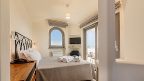 Une chambre d’hôtel avec un lit, un bureau avec un téléphone, une télévision et une fenêtre donnant sur un paysage agréable.