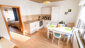 Una cocina compacta con comedor, piso de madera y muebles de cocina blancos.
