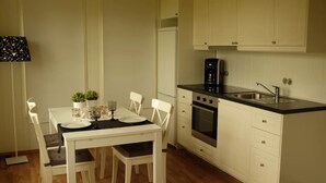 Una cocina compacta con armarios blancos, una encimera negra y un horno empotrado.