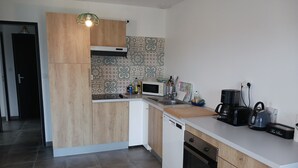Une cuisine moderne dotée d’un îlot central, de meubles blancs, d’un crédence décorée et de divers appareils, notamment un four à micro-ondes, une machine à café et une bouilloire.