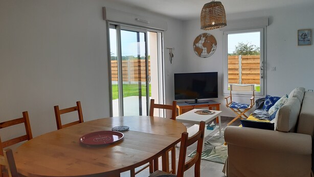 Un coin repas comprenant une table ronde en bois, des chaises, un téléviseur et un canapé.