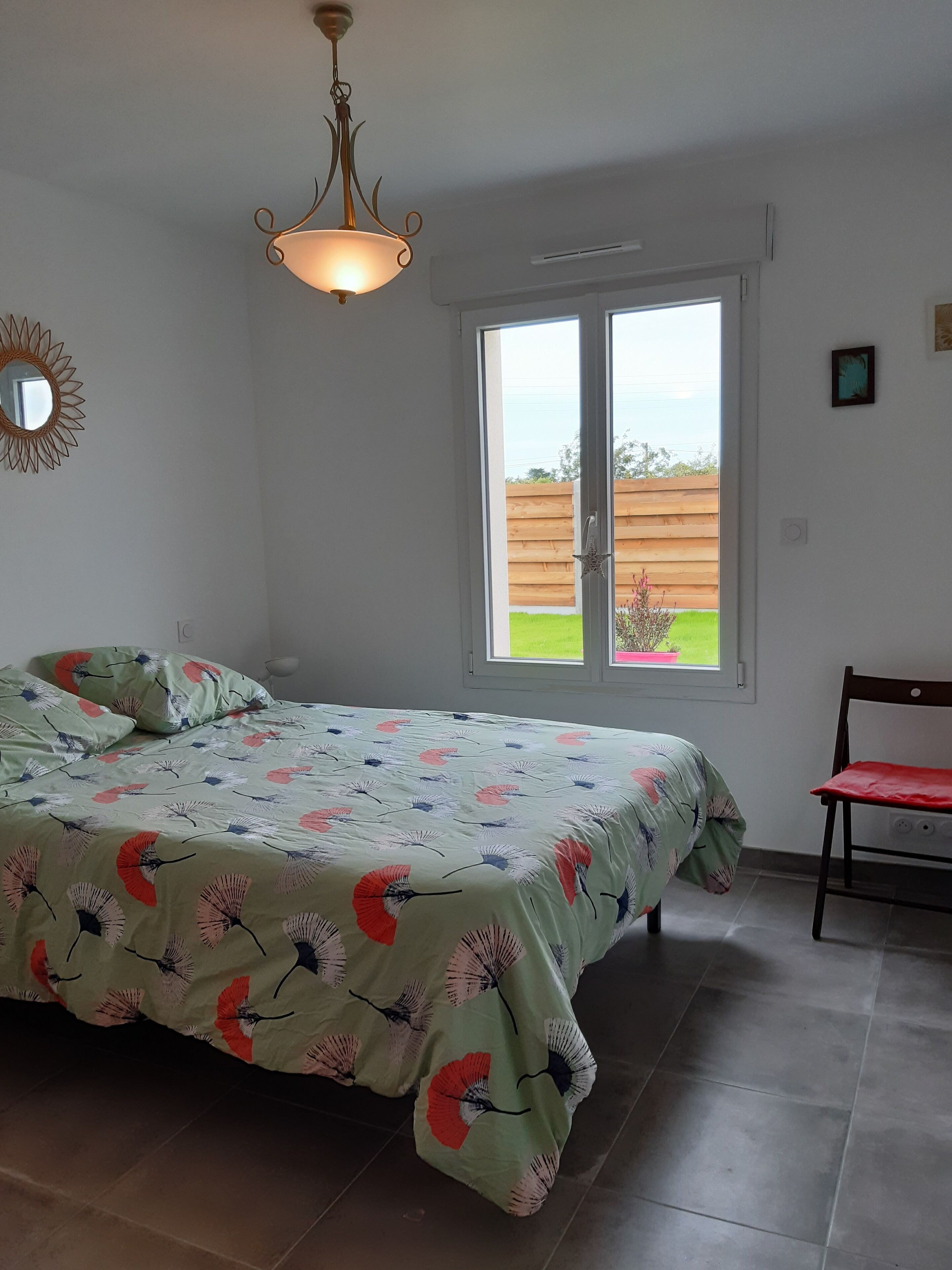 Une chambre à coucher avec un lit, une chaise, une fenêtre et un luminaire au plafond.