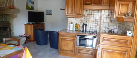 A kitchen with wooden cabinets, a tiled backsplash, a built-in oven, and a television on a wooden stand.
