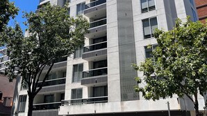Un edificio moderno de varios pisos con balcones, ventanas amplias y acceso a un garaje.