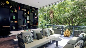 Un área de estar exterior moderna con un sofá, sillas, una mesa de comedor y una estantería llena de objetos decorativos.