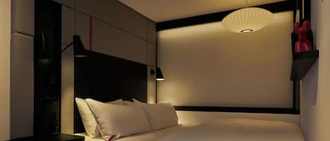 Une chambre d’hôtel moderne dotée d’un grand lit, d’un bureau avec une chaise, d’une télévision et d’un luminaire au plafond au design original.