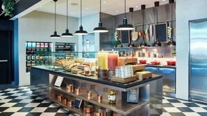 Un área de cocina moderna con una isla central, iluminación colgante y una variedad de alimentos y condimentos.