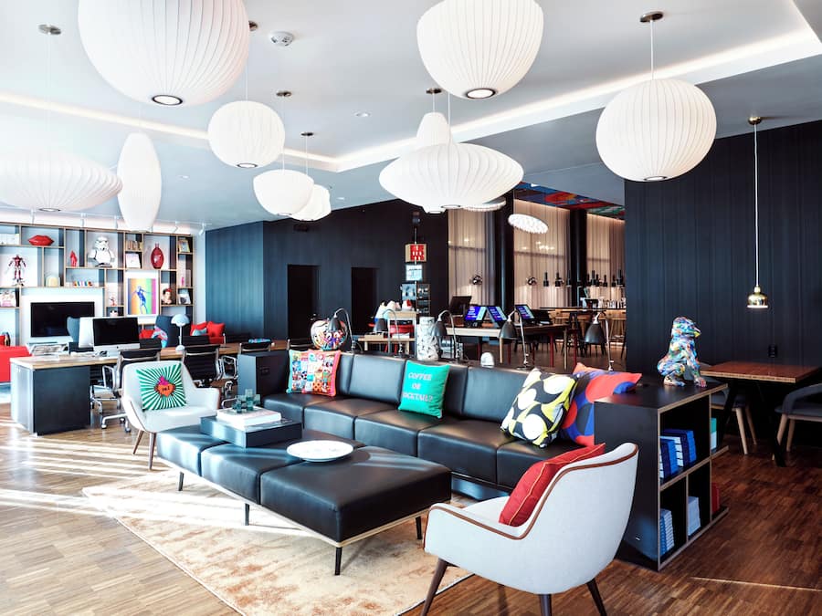 Un hall d’hôtel moderne avec un canapé d’angle, une table basse et un coin bar.