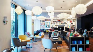 En modern hotellobby med olika typer av sittmöbler, en öppen spis och dekorativa föremål utställda på hyllor.