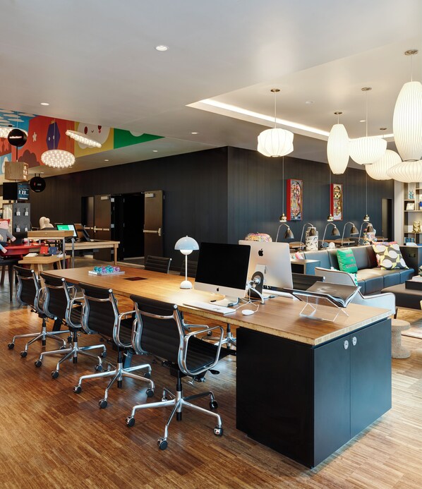 A modern office space with a long wooden conference table, multiple office chairs, and a variety of lighting fixtures.