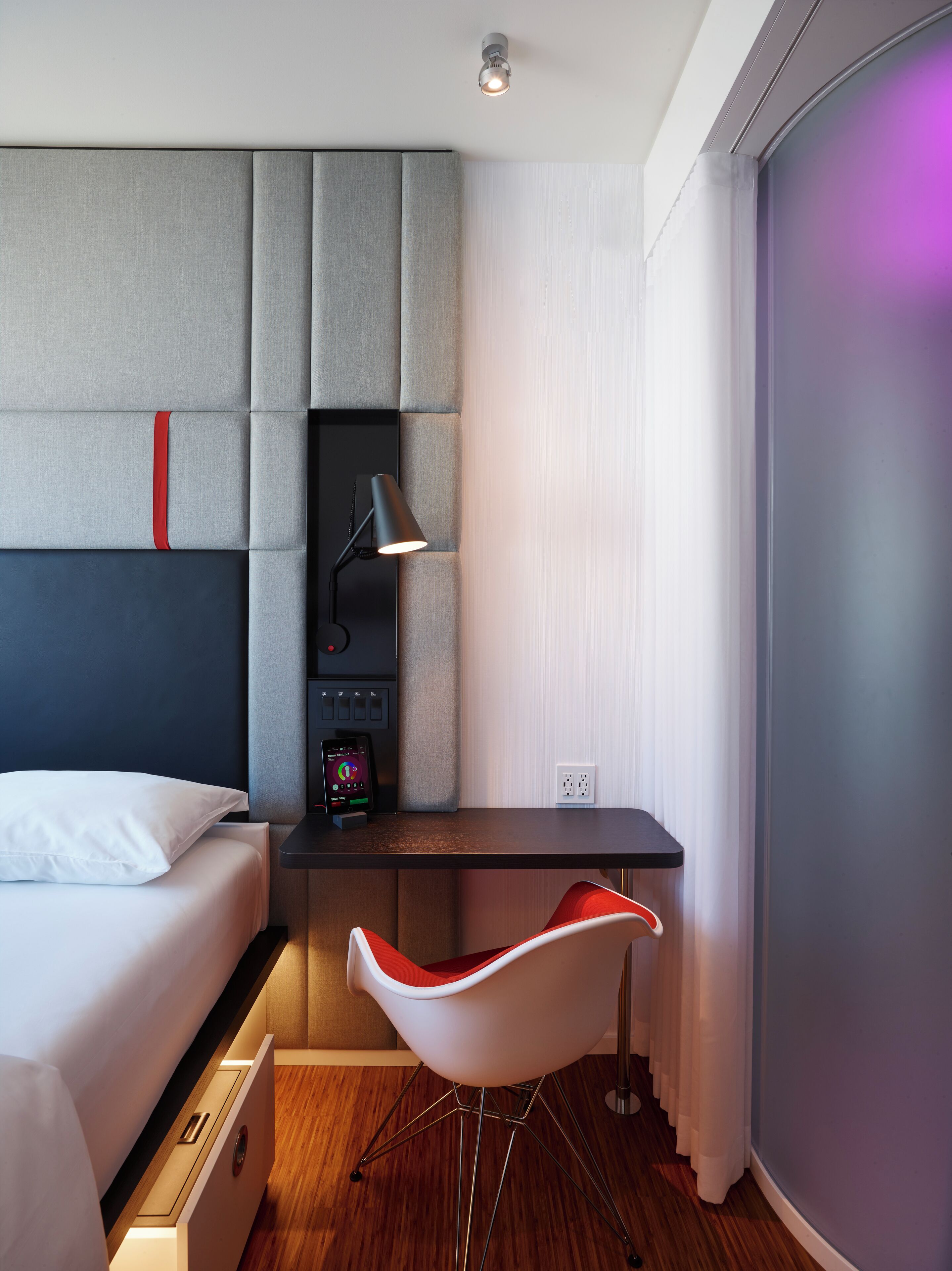Une chambre d’hôtel moderne équipée d’un lit, d’un bureau, d’une chaise et d’une table de chevet.