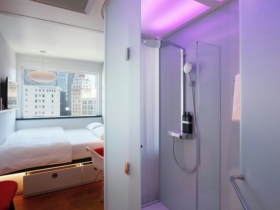 Een moderne hotelkamer met een groot bed, een douche en uitzicht over de stad.