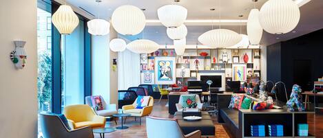 A modern interior with multiple seating areas, a central table, and a bookshelf with various items.