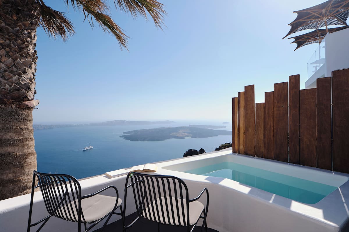 A poolside area with two chairs, a wooden fence, and a view of the sea and islands.
