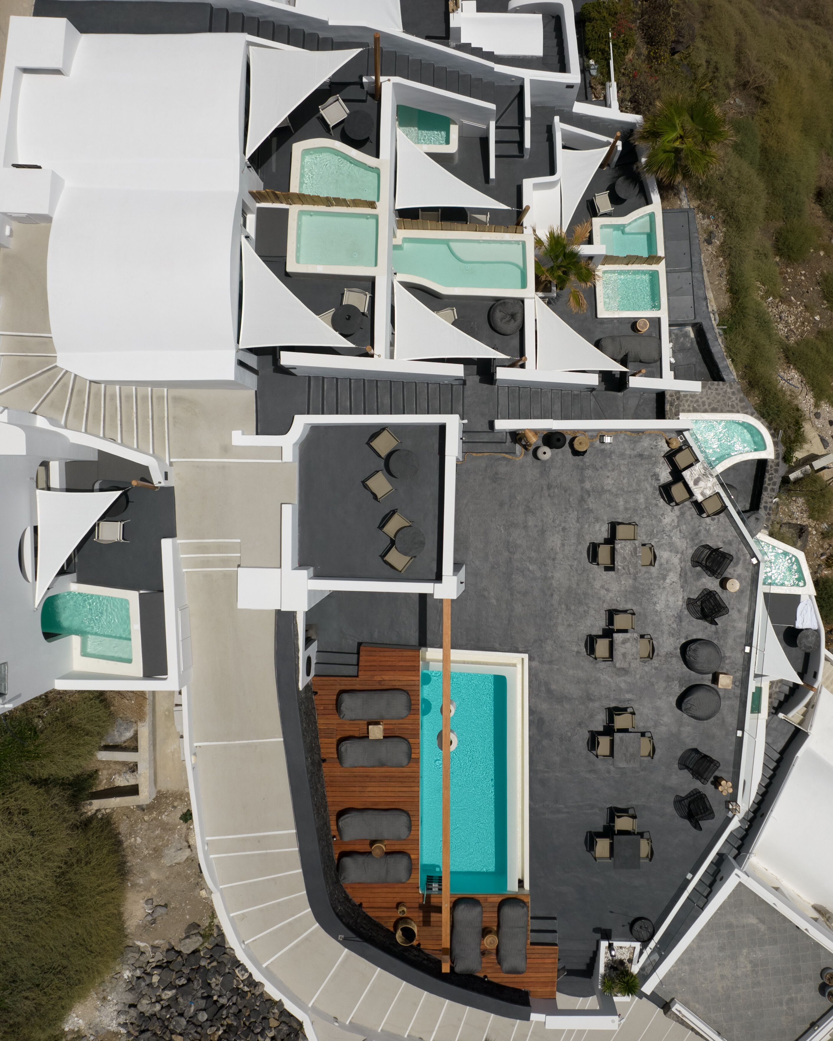Vista aérea de un resort con varias piscinas, tumbonas y una zona de terraza de madera.