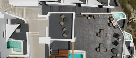 Vista aérea de un resort con varias piscinas, tumbonas y una zona de terraza de madera.