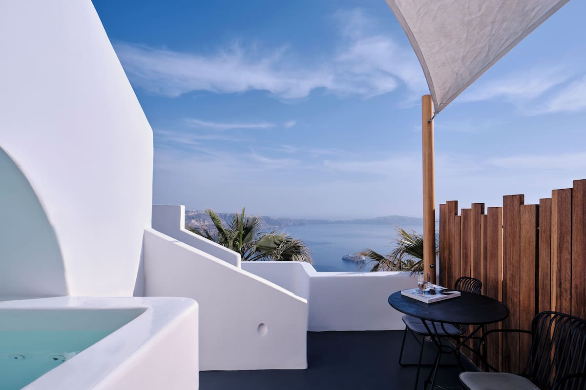A modern outdoor seating area with a view of the sea and mountains.