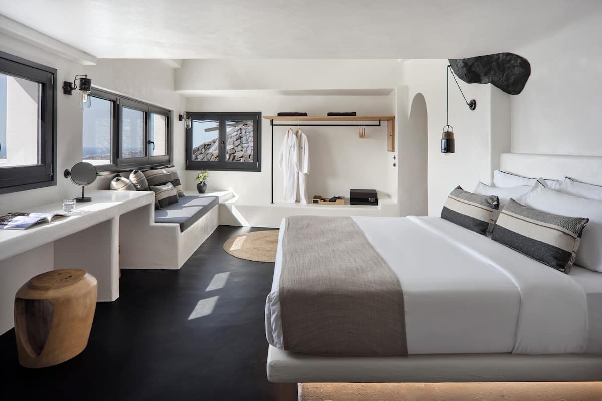 A modern bedroom with a bed, bedside table, and a desk with a chair.