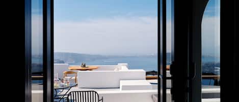 A modern outdoor seating area with a view of the sea and cliffs.