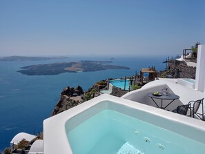 A luxurious outdoor jacuzzi with a clear view of the sea and islands. - Stella Rocca A Mare (Santorini)
