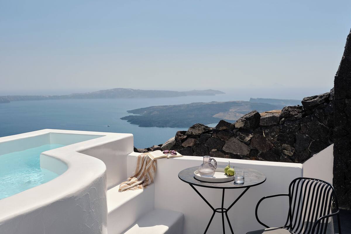 A white infinity pool with a clear view of the sea and islands in the distance.