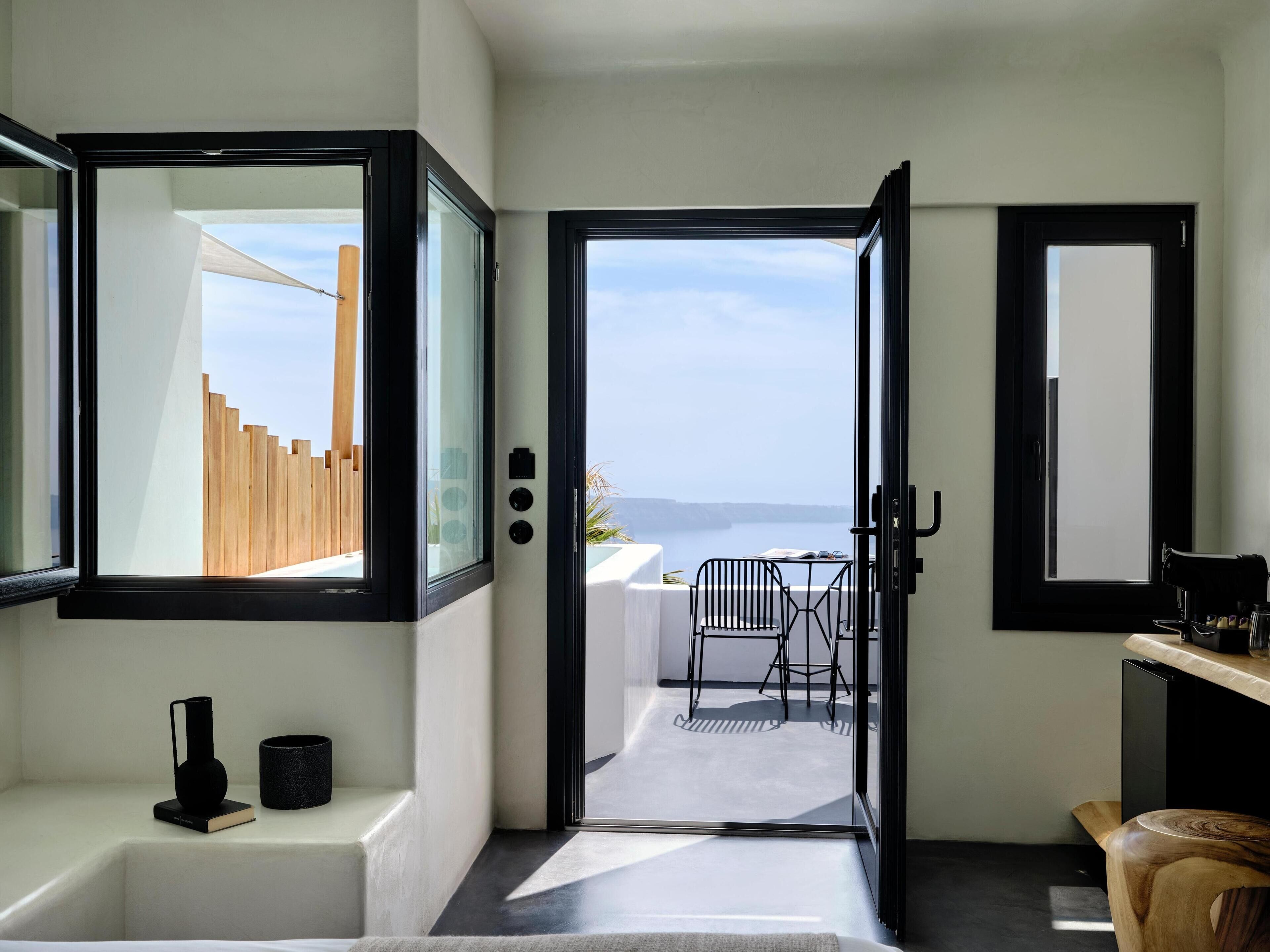 A modern interior with a view to the sea, a minimalist design, and a small outdoor seating area.