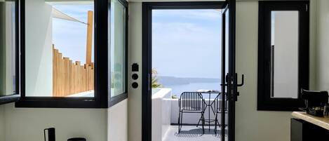 A modern interior with a view to the sea, a minimalist design, and a small outdoor seating area.