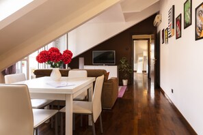 A modern dining area with a white table and chairs, a brown sofa, and a potted plant. - notaMi - Oskar Home - Tre Ponti (Milan)
