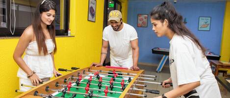 A room with a foosball table, a window, and a blue wall.